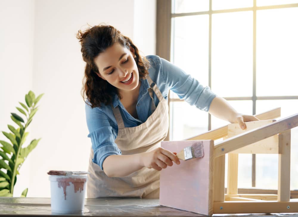 mujer pintando mostrando como hacer un taburete de madera