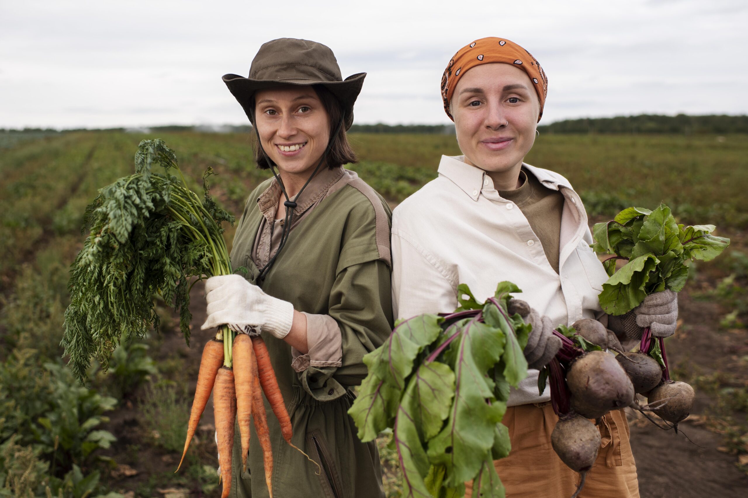 Dos mujeres rurales cogiendo las hortalizas que han cultivado. 